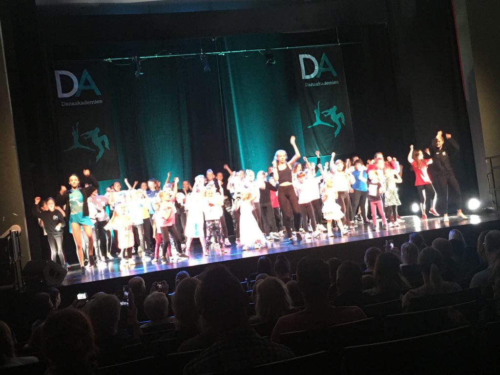 Stor grupp barn och ungdomar dansar på en scen