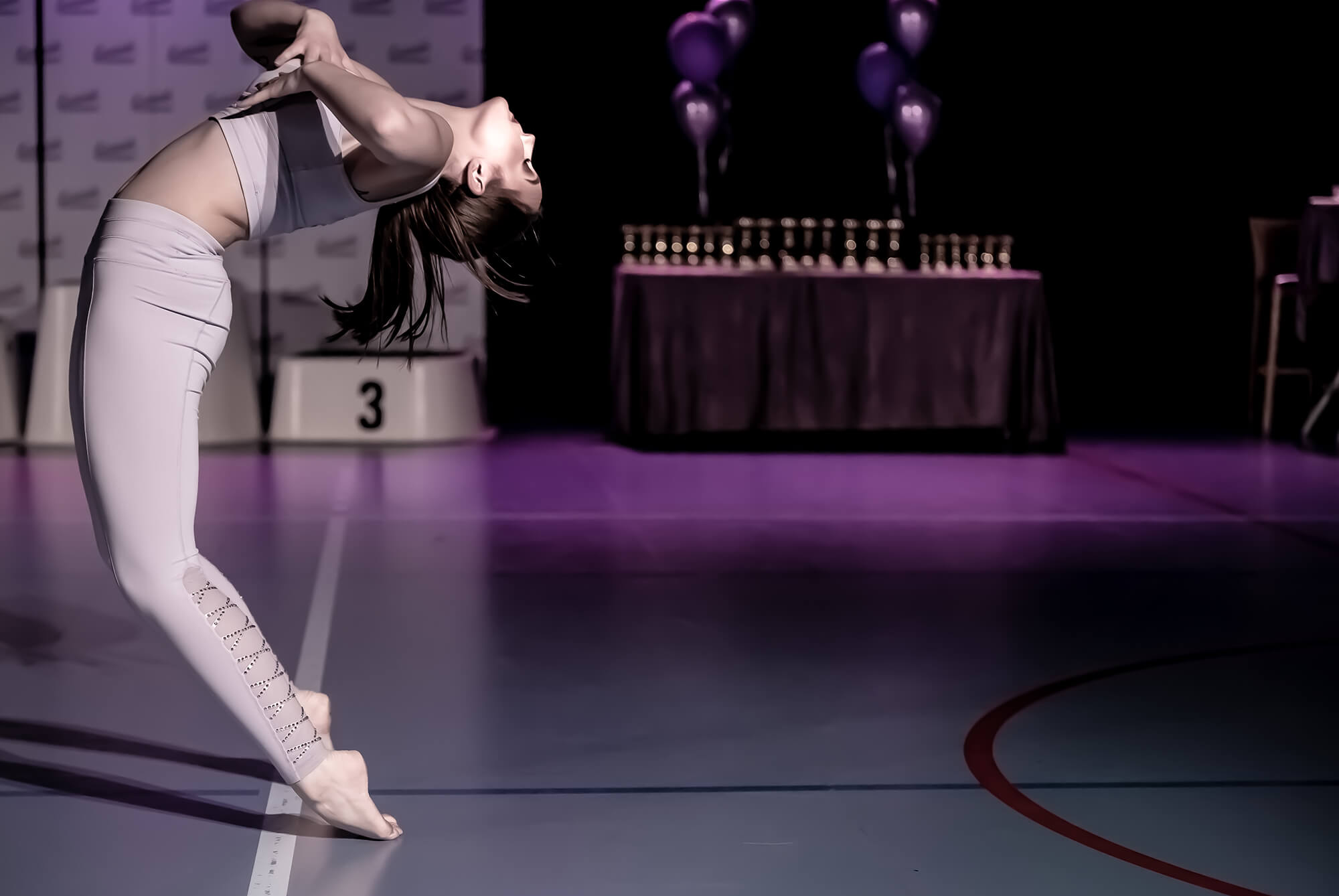 Tjej står på tå bakåtlutad i dans