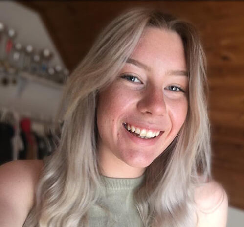 Tjej med ljust hår och linne ler