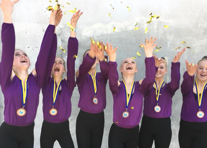 Personer i lila tröjor med medaljer